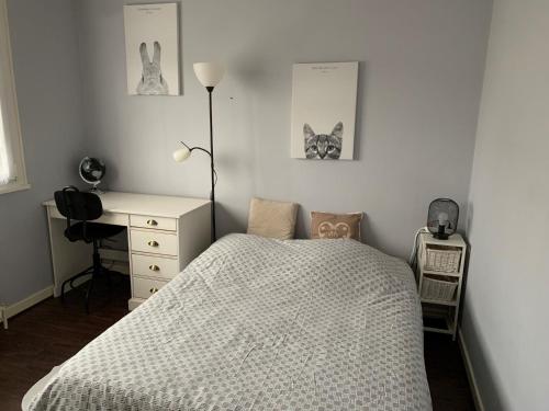 吕克瑟伊莱班Maison chaleureuse avec cheminée et extérieur的一间卧室配有一张床、一张书桌和两张图片