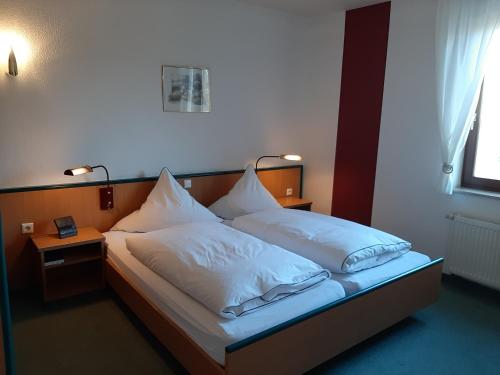 卡塞尔Hotel & Restaurant Eichholz的一间卧室配有带白色床单和枕头的床。