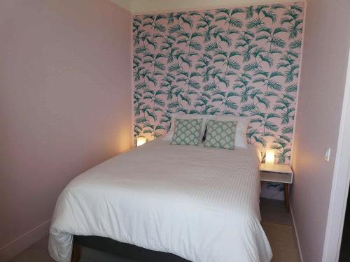 阿罗芒什莱班Appartement de standing - avec terrasse et vue mer的卧室配有白色床和花卉壁纸
