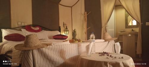 梅尔祖卡Sahara Tours luxury camp的一间卧室配有一张大床,配有两张桌子和一张带安息箱的床