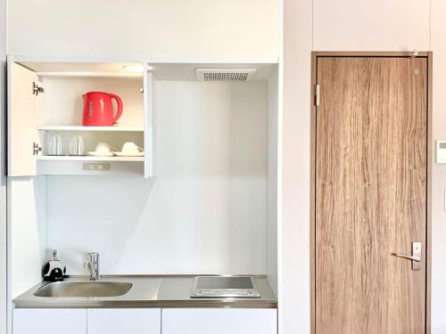 直岛町斯帕奇公寓的白色的厨房,配有水槽和红色的器具