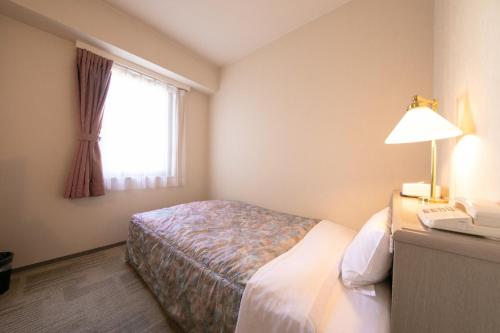都城市Main Hotel - Vacation STAY 82545的酒店客房配有一张床、一张书桌和一部电话