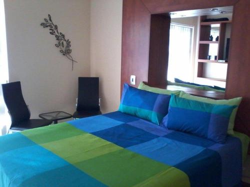 比勒陀利亚Genie's Nest 1的一间卧室配有蓝色和绿色的床和两把椅子