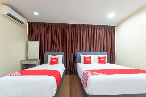 JasinOYO 90380 Hotel Jasin的宿舍间内的两张床,配有红色枕头