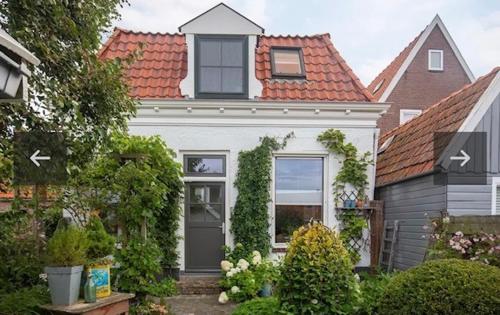 欣德洛彭Uit Alle Windstreken的一座白色的小房子,拥有橙色的屋顶