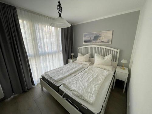 奥斯赛拜-屈隆斯博恩Pier Kühlungsborn的一间卧室配有带白色床单和枕头的床。