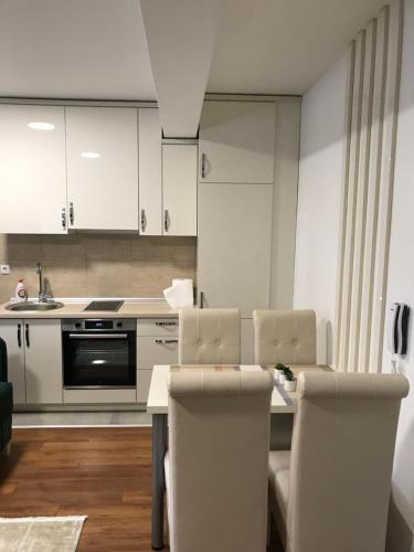新帕扎尔Green Apartment的厨房配有白色橱柜和桌椅