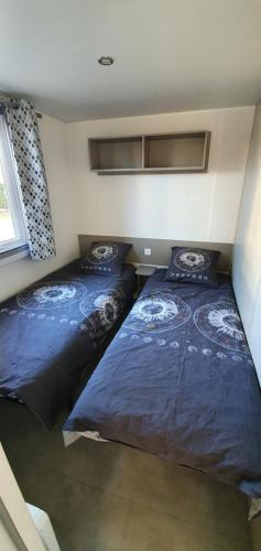 圣让-德蒙MH 149 4 pers camping Bois Dormant confort et détente的配有蓝色棉被的客房内的两张床
