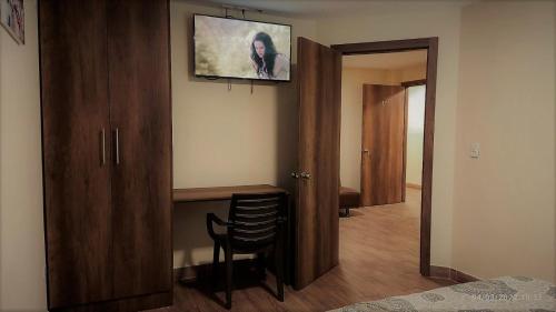 卡扬贝Apart Cayambe的一间房间,墙上设有一张桌子和一台电视机