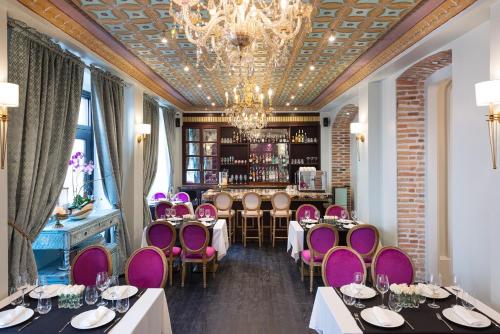 昆卡Itza Hotel Boutique Internacional的一间设有紫色桌椅的餐厅和一间酒吧