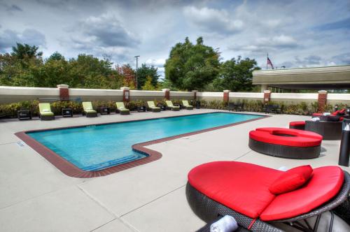 本赛霖姆Inn at Fox Chase - BW Premier Collection的一座大楼前的游泳池,配有椅子和红色的搁脚凳