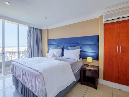 德班The Sails Apartment 2 Bed 2 Bath Seaview Apartment - C5的一间卧室配有一张大床和蓝色床头板