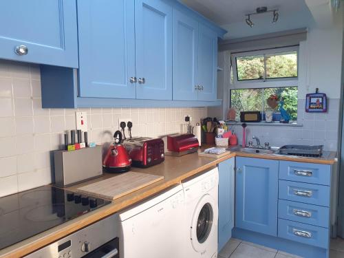 科克Idyllic Inchydoney Beach Cottage - Amazing sea views, path to beach!的厨房配有蓝色橱柜和洗衣机。