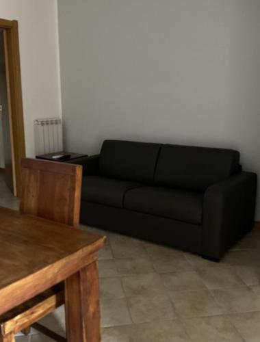 福利尼奥Silio 12的客厅配有一张黑色沙发,设有一张桌子
