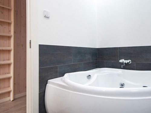 宝可波8 person holiday home in B rkop的浴室铺有黑色瓷砖,配有白色浴缸。