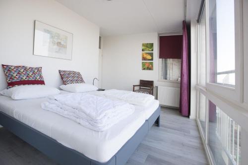 布雷斯肯斯Kustverhuur, Appartement aan zee, Port Scaldis 05042的一间卧室配有一张带白色床单的床和一扇窗户。
