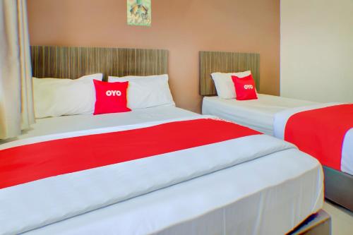 新山Super OYO 89985 Js Hotel的配有红色和白色枕头的客房内的两张床