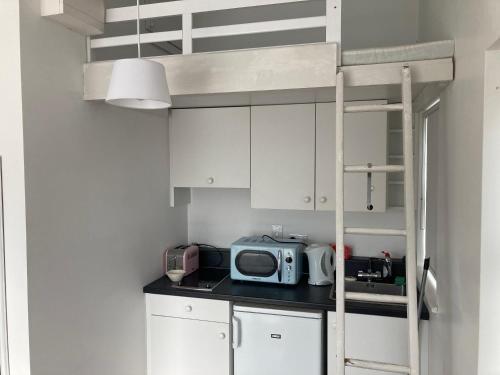 邓莫尔东Sandy Cove的小厨房配有白色橱柜和一张双层床。