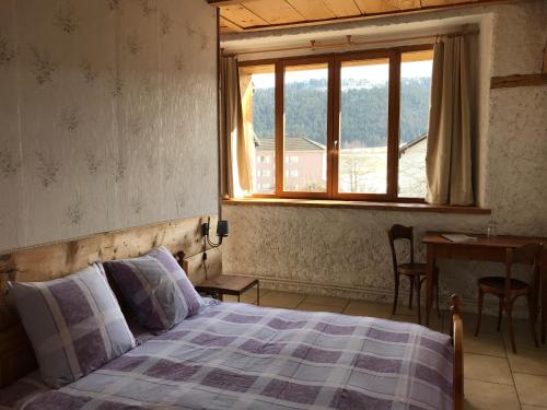 La SagneHôtel Von Bergen的一间卧室设有一张床、一个窗口和一张桌子