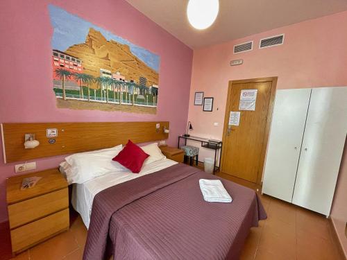 阿利坎特Pensión Alicante San Nicolás的卧室配有一张床,墙上挂有绘画作品