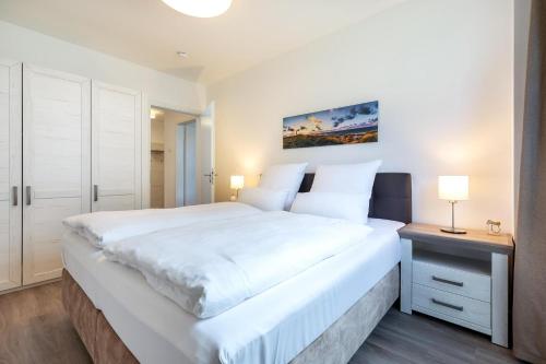 博尔滕哈根Aparthotel Ostseeallee Aparthotel Ostseeallee 4-31的卧室配有一张白色的大床和床头柜。
