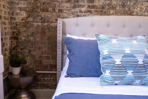 新奥尔良French Quarter Delight 8的一张带蓝色和白色枕头的床和砖墙