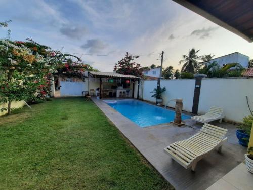 特赖里casa praia de guajiru的后院设有游泳池和2个长椅