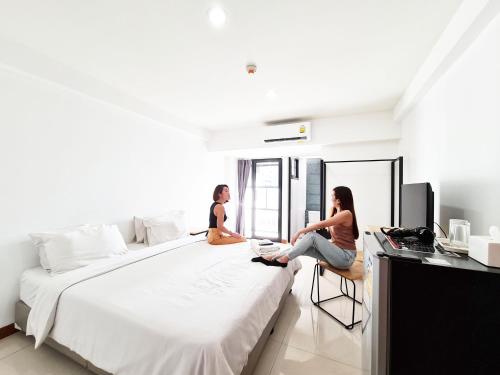 曼谷廊曼酒店的两个女人坐在卧室的床上
