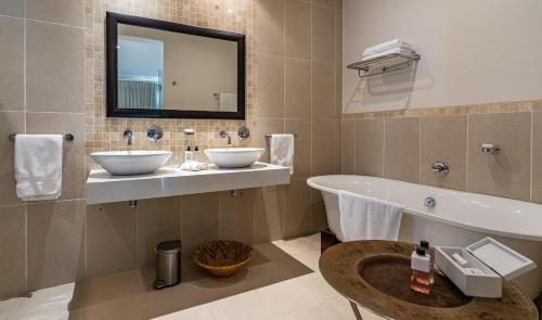 开普敦Sea Five Boutique Hotel的浴室设有2个水槽、浴缸和镜子
