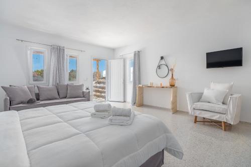 米克诺斯城IL Vento Suites的白色的卧室配有一张白色的大床和一张沙发