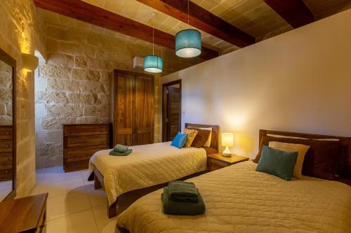 MunxarAndrea Luxury Holiday Farmhouse的一间卧室设有两张床和石墙