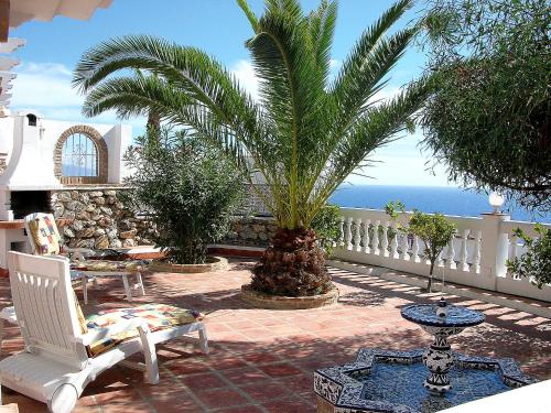 阿尔姆尼卡米莫莎阿尔穆涅卡尔别墅的一个带椅子和棕榈树的庭院和大海