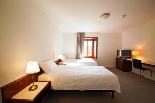洛桑Galion Hôtel & Restaurant的酒店客房配有两张床和一张书桌