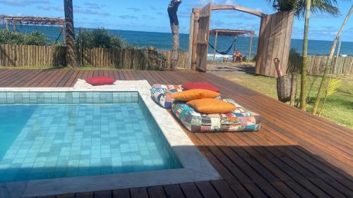 卡拉伊瓦Villa do Sossego - Caraíva的海滩旁游泳池畔的一张床