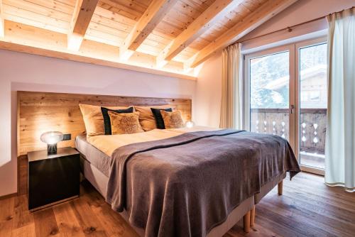 迈尔霍芬Chalet Alpendomizil Ahorn的一间卧室设有一张大床和一个大窗户