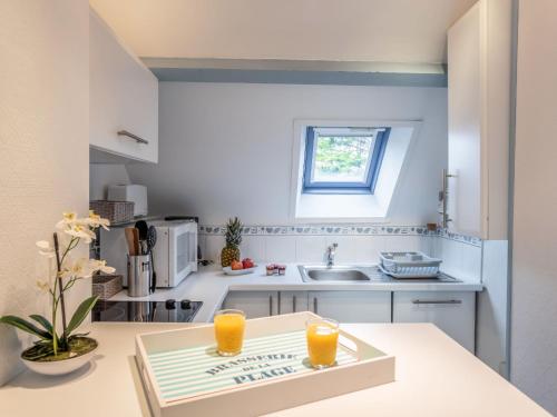 卡纳克Apartment Les Pins-3 by Interhome的厨房配有一张桌子和两杯橙汁