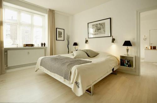 哥本哈根ApartmentInCopenhagen Apartment 1167的白色的卧室设有一张大床和一个窗户