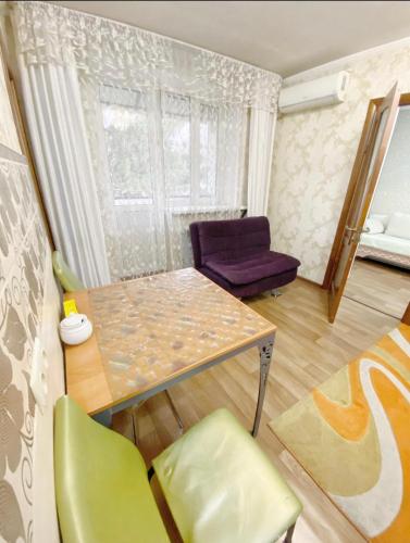 阿拉木图Apartments Ahmetova 4 21的客厅配有桌子和紫色椅子
