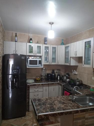 利马Chakana Family Home 2 Lima Airport的厨房配有黑冰箱和白色橱柜。