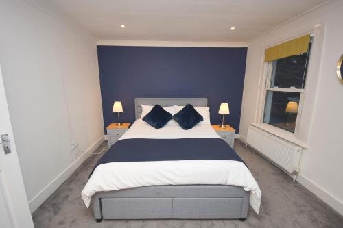 伦敦JB stays Greenwich, 3 bed house,ideal for contractors and family的一间卧室配有一张带蓝色墙壁的大床