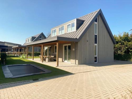 坎珀兰luxe Villa Maroma Regal aan Veerse meer met 4 Ebikes GasBBQ & EV laadpaal的房屋设有 ⁇ 屋顶和庭院