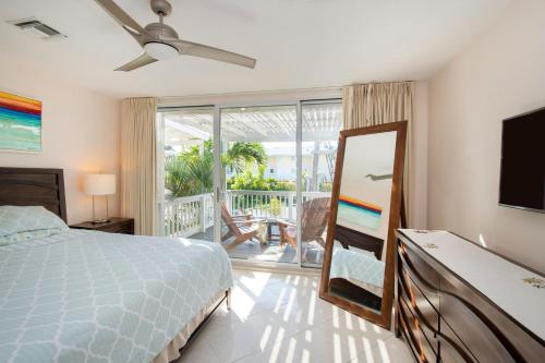 乔治敦Beach Living at Island Pine Villas BLAW的一间卧室配有一张床、一台电视和一个阳台
