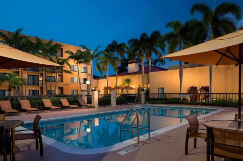 布卡拉顿Sonesta Select Boca Raton Town Center的一个带桌子和遮阳伞的酒店游泳池