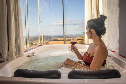 Serra de São BentoChalé Formoso - Chalé Romântico com Hidromassagem的坐在浴缸里的女人,喝一杯葡萄酒