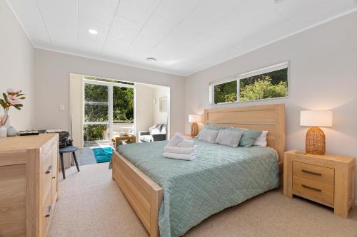 Waipu CoveFrancis Orchard Country Stay - Waipu Holiday Home的一间卧室配有一张床、一张书桌和两个窗户。