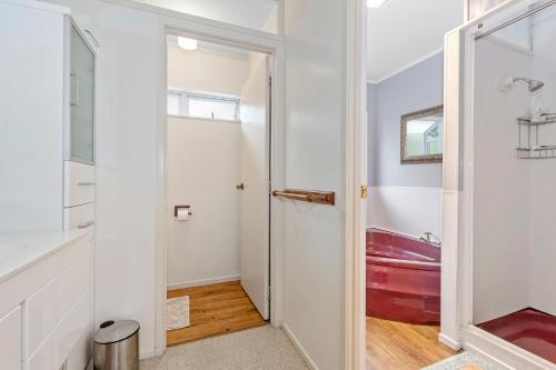 Waipu CoveFrancis Orchard Country Stay - Waipu Holiday Home的浴室设有通往红色浴缸的门