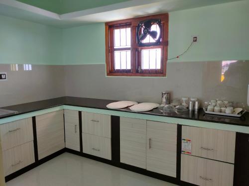 科代卡纳尔MISBA HOMESTAY的厨房配有带白色橱柜的柜台和窗户。