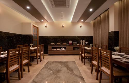 钦奈The Madras Grand的餐厅设有木桌、椅子和柜台