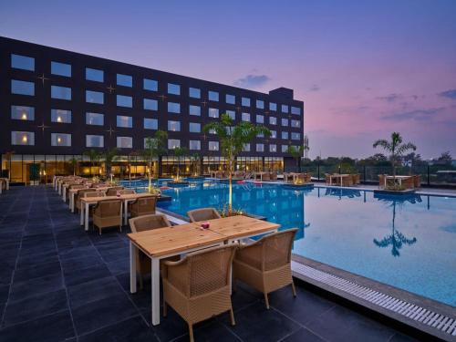 印多尔Essentia Luxury Hotel Indore的酒店设有带桌椅的游泳池