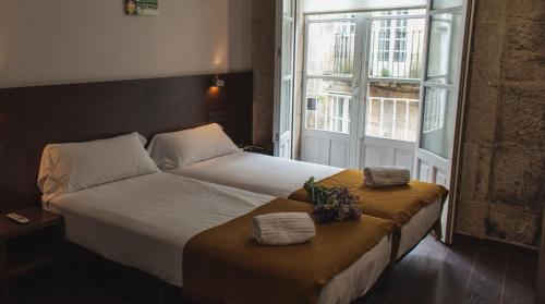 圣地亚哥－德孔波斯特拉潘诗恩阿卡萨度佩瑞格里诺酒店的一间卧室配有带2条毛巾的床和窗户。